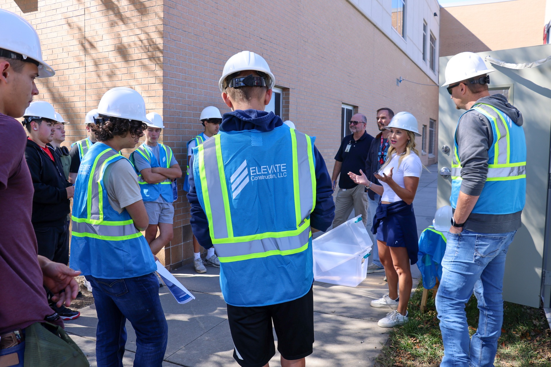 The owners of Elevate Construction talking with a group of high school students in front of their construction site at Lewis Central High School.