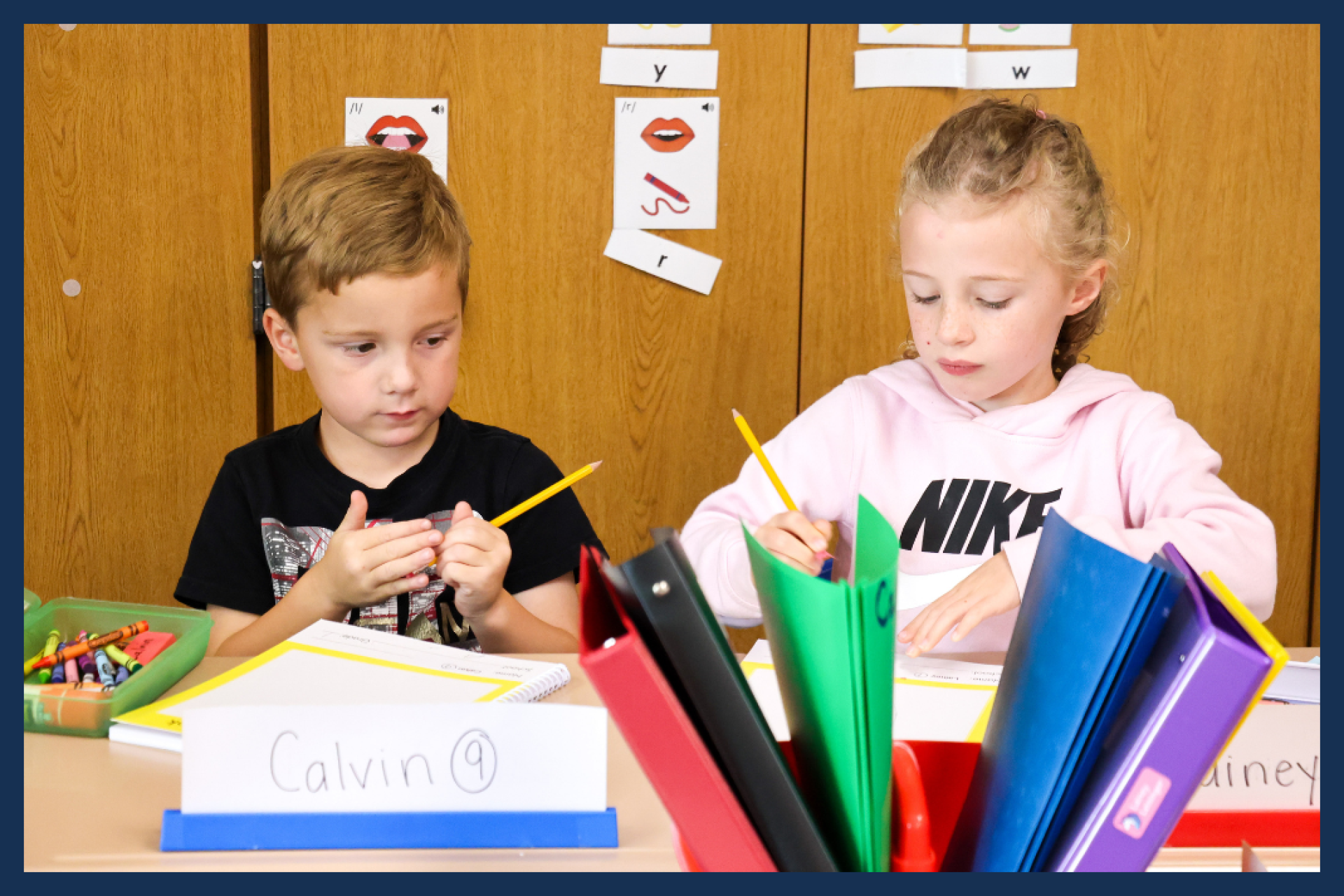 Two first grade students writing at their desks,