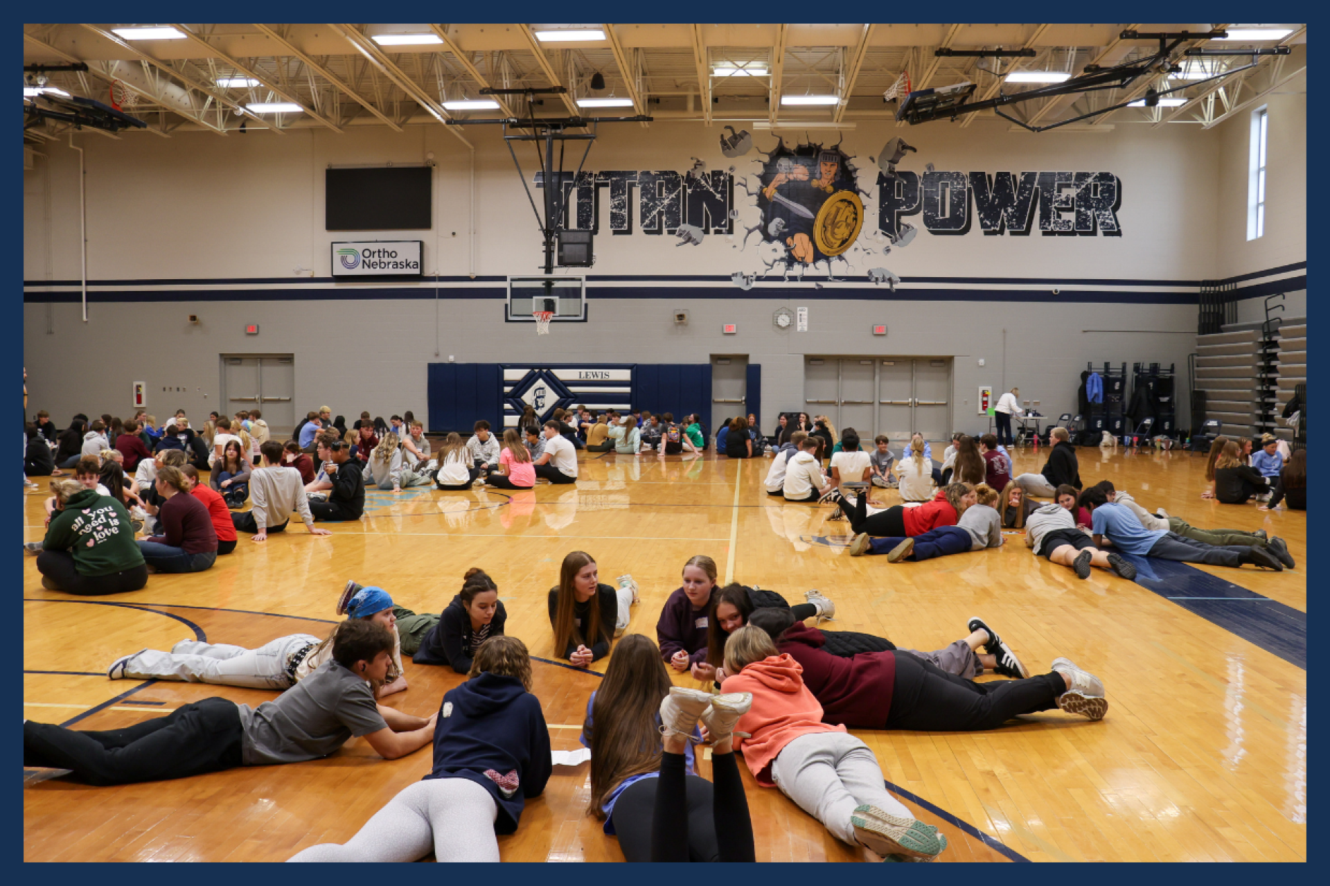 Groups of high school students sitting on the gym floor doing group activities.