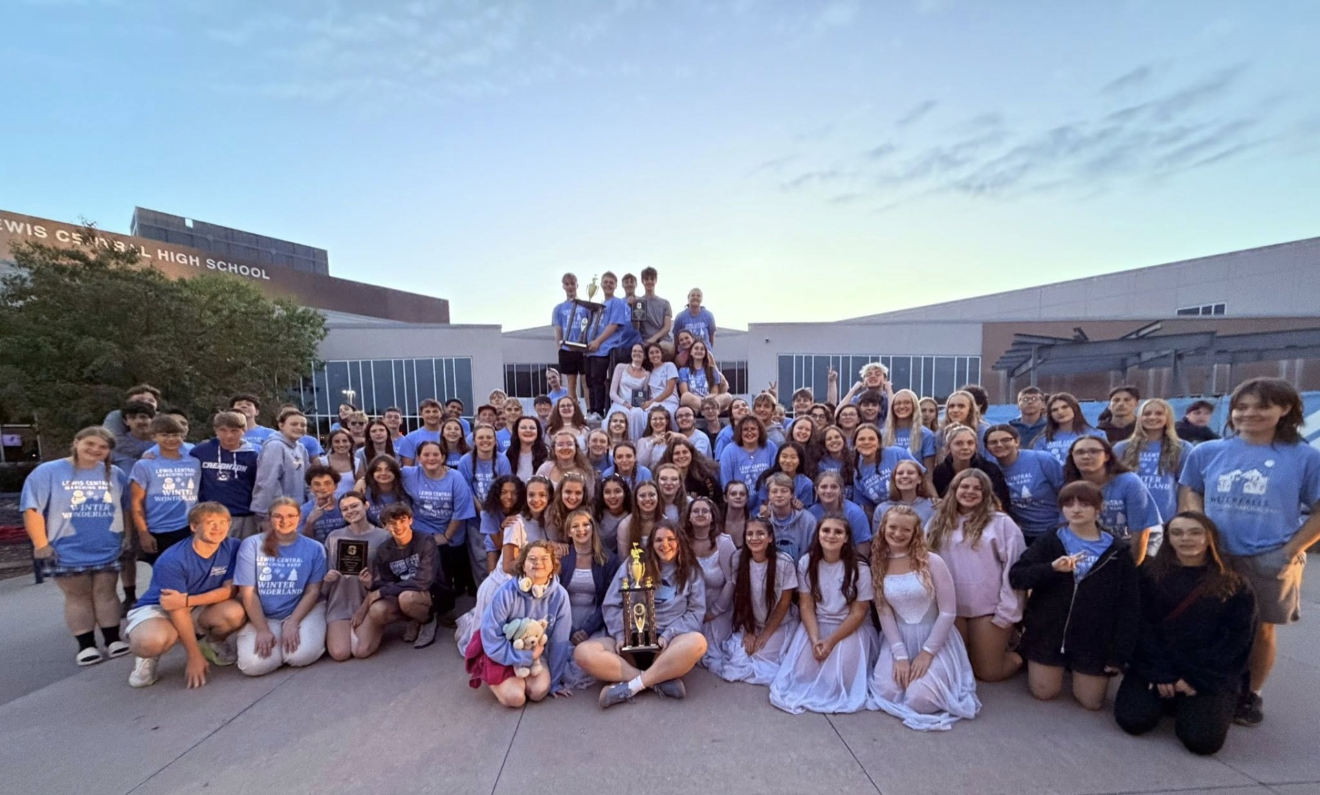 LCHS marching band students posing in front of Lewis Central High School to celebrate their victory