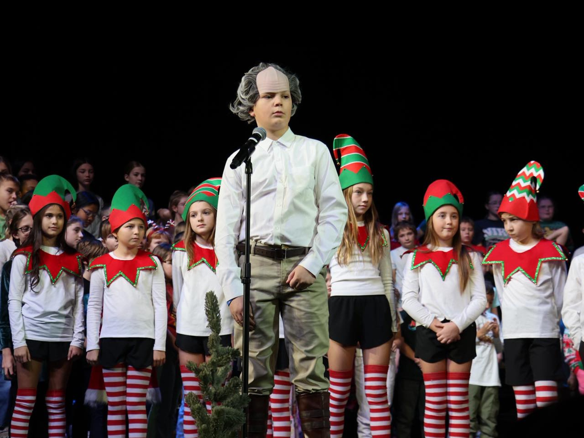 Elementary students dressed up as elves on the stage performing "Lights, Camera, Christmas!"