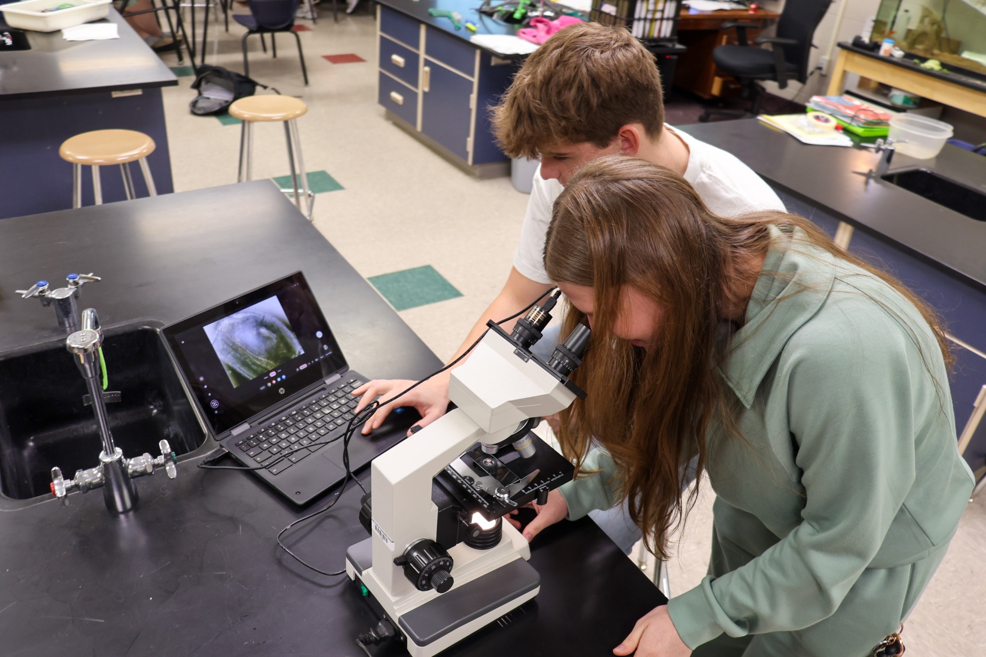 Two high school students utilizing the new microscope cameras to look at specimens.