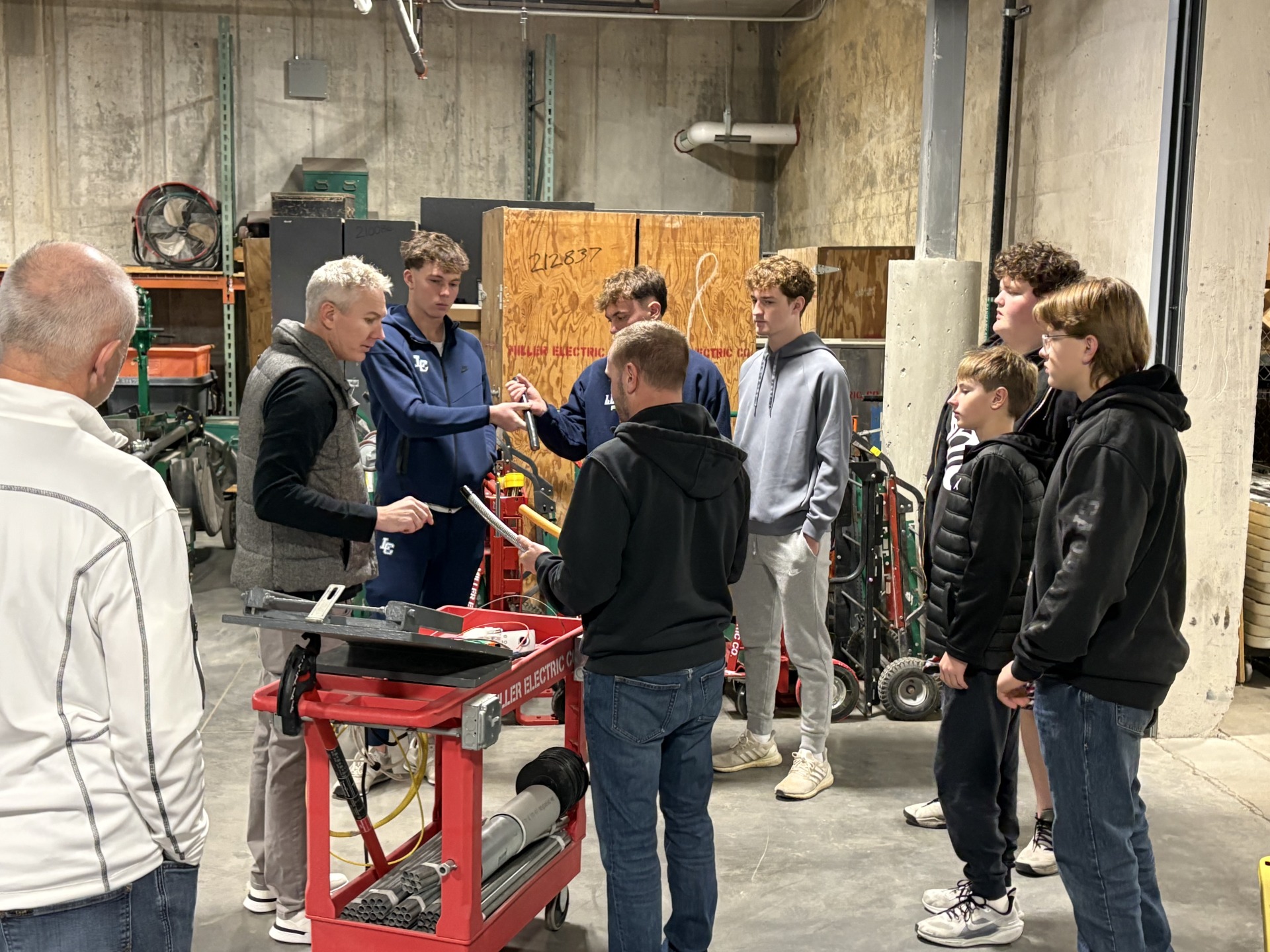 A group of seven high school students looking at various types of pipe used by electricians at Miller Electric.