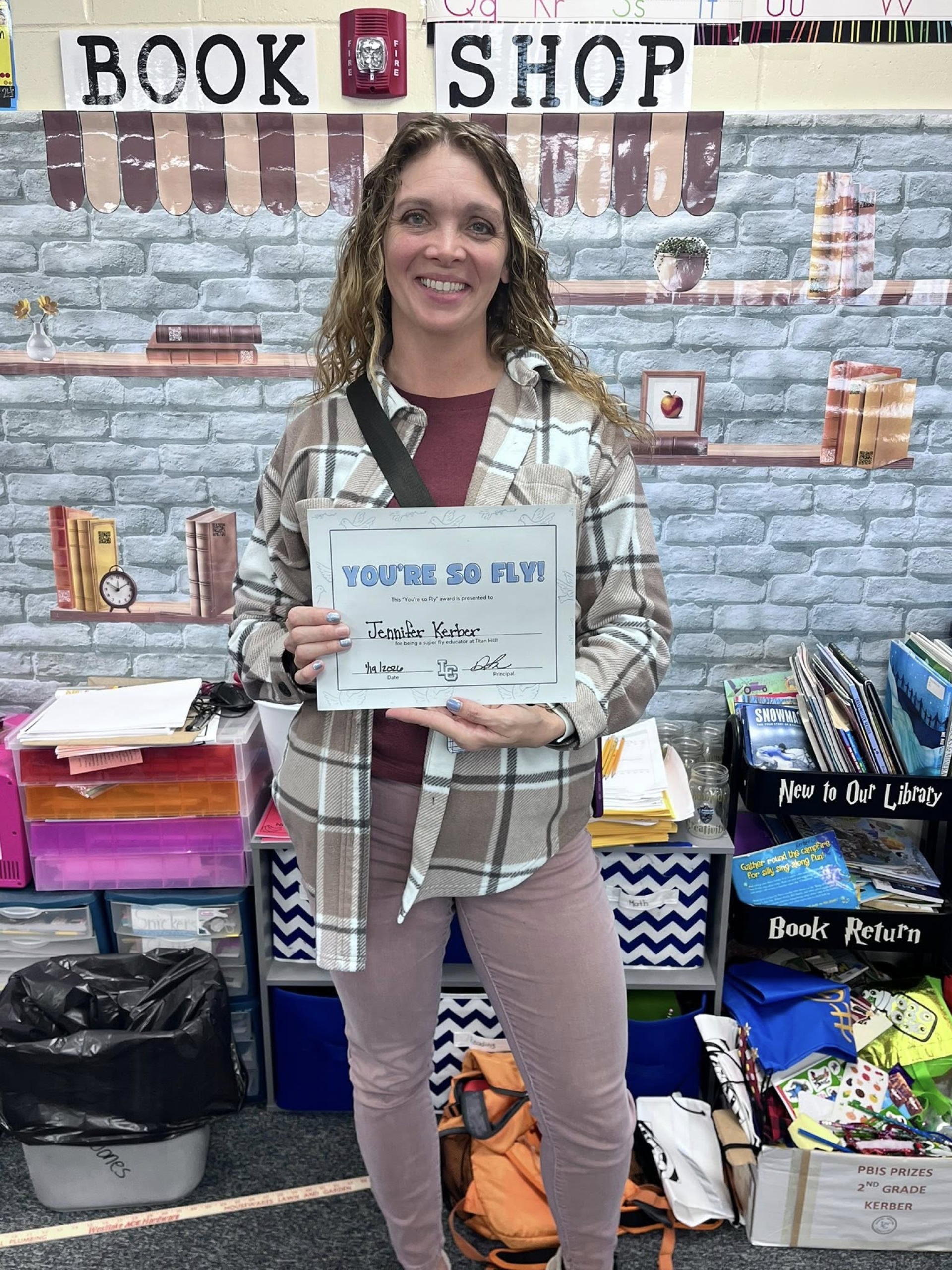 Mrs.Kerber, 2nd grade teacher, posing with her "You\'re so Fly" staff award.
