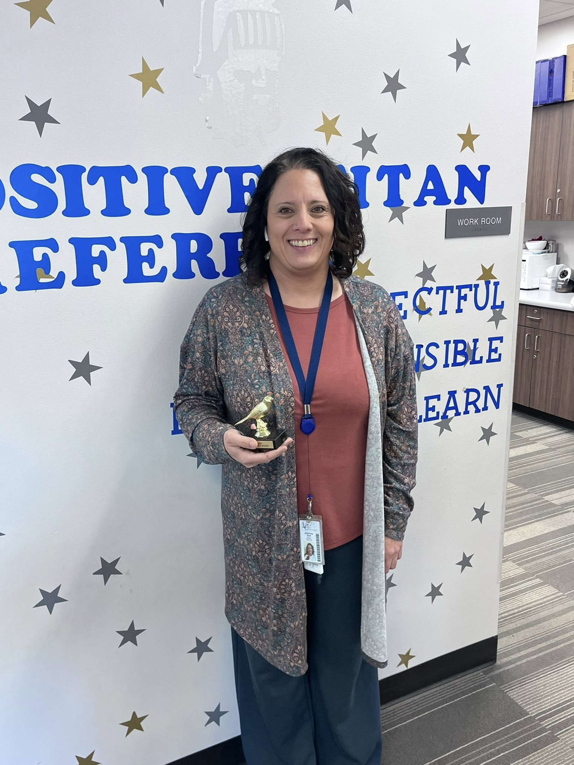 Ms. Beam, office staff member, posing with her "You\'re So Fly" staff award.