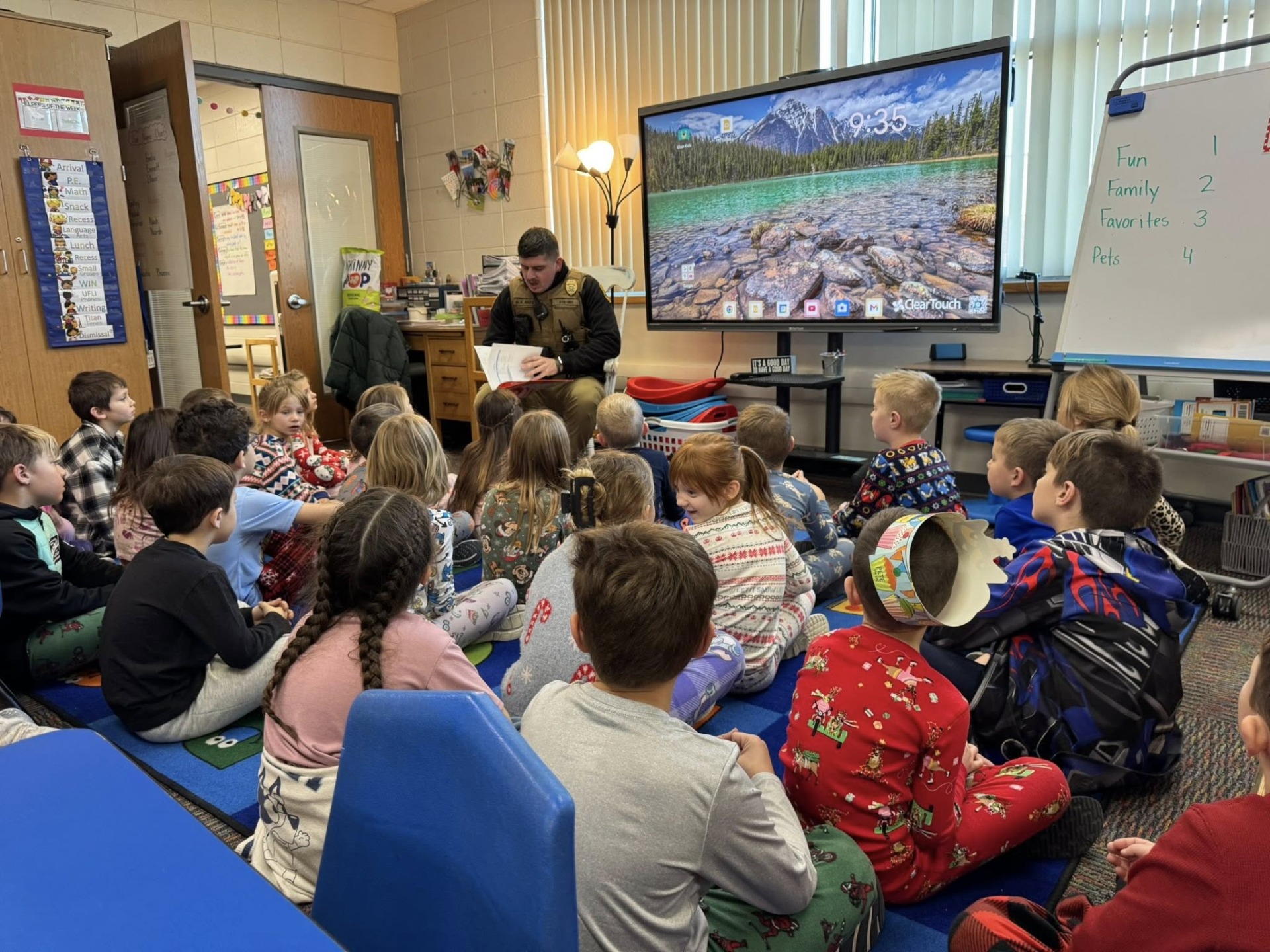 Iowa State Patrol Officer Raes reading a story to a classroom full of children.
