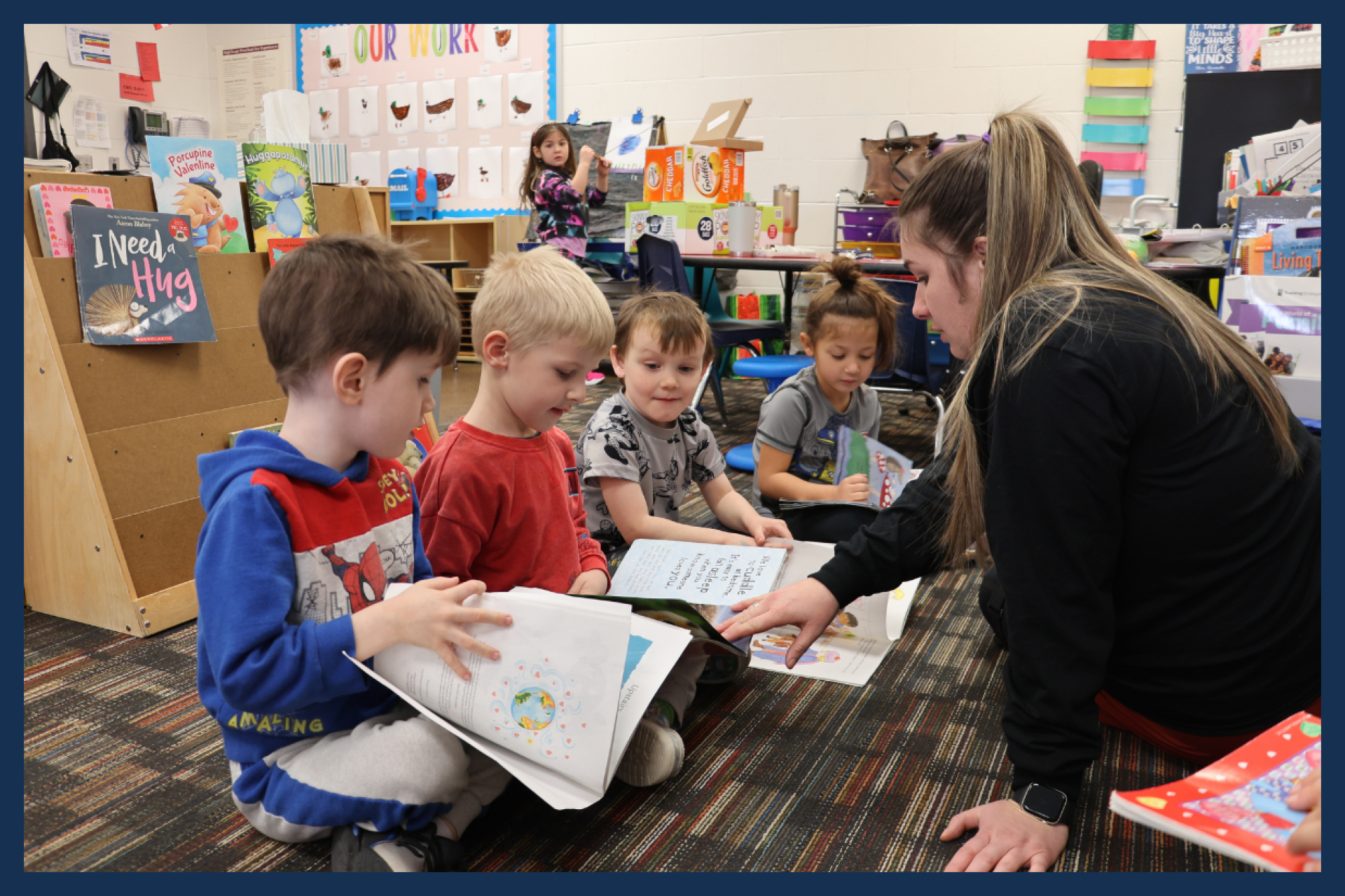Preschool students reading books with their teacher.