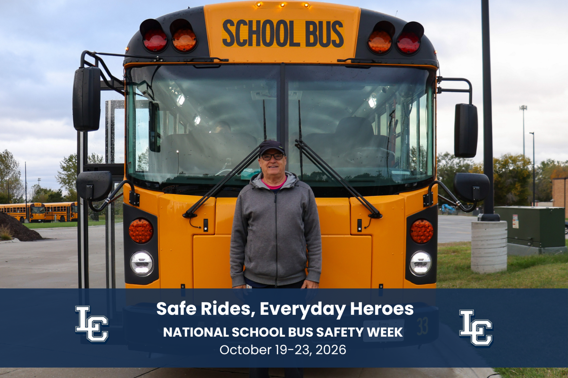 A school bus driver standing in front of a bus.