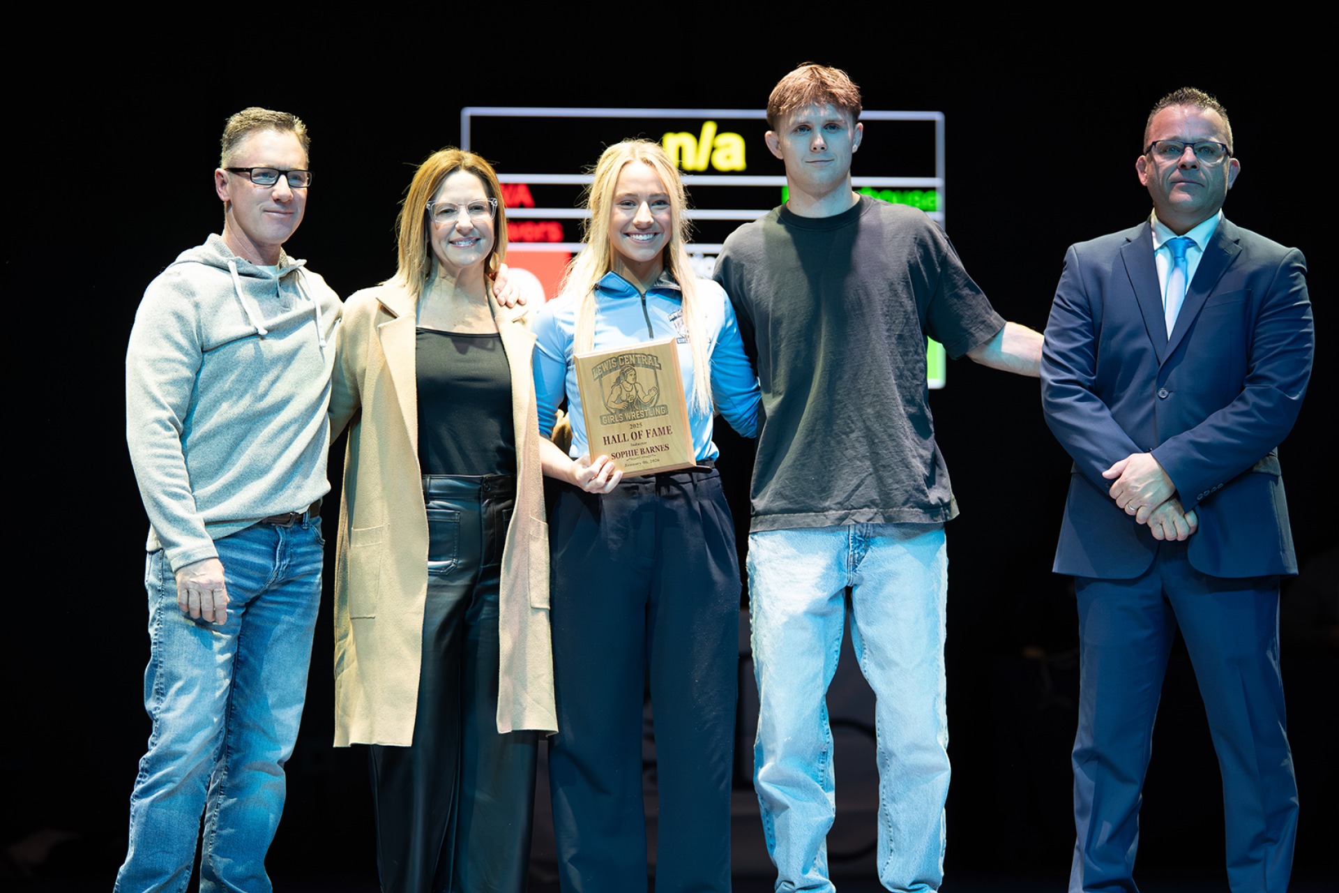 Sophie Barnes, her parents, boyfriend, and coach Dean Leaders posing on stage with her Hall of Fame plaque.