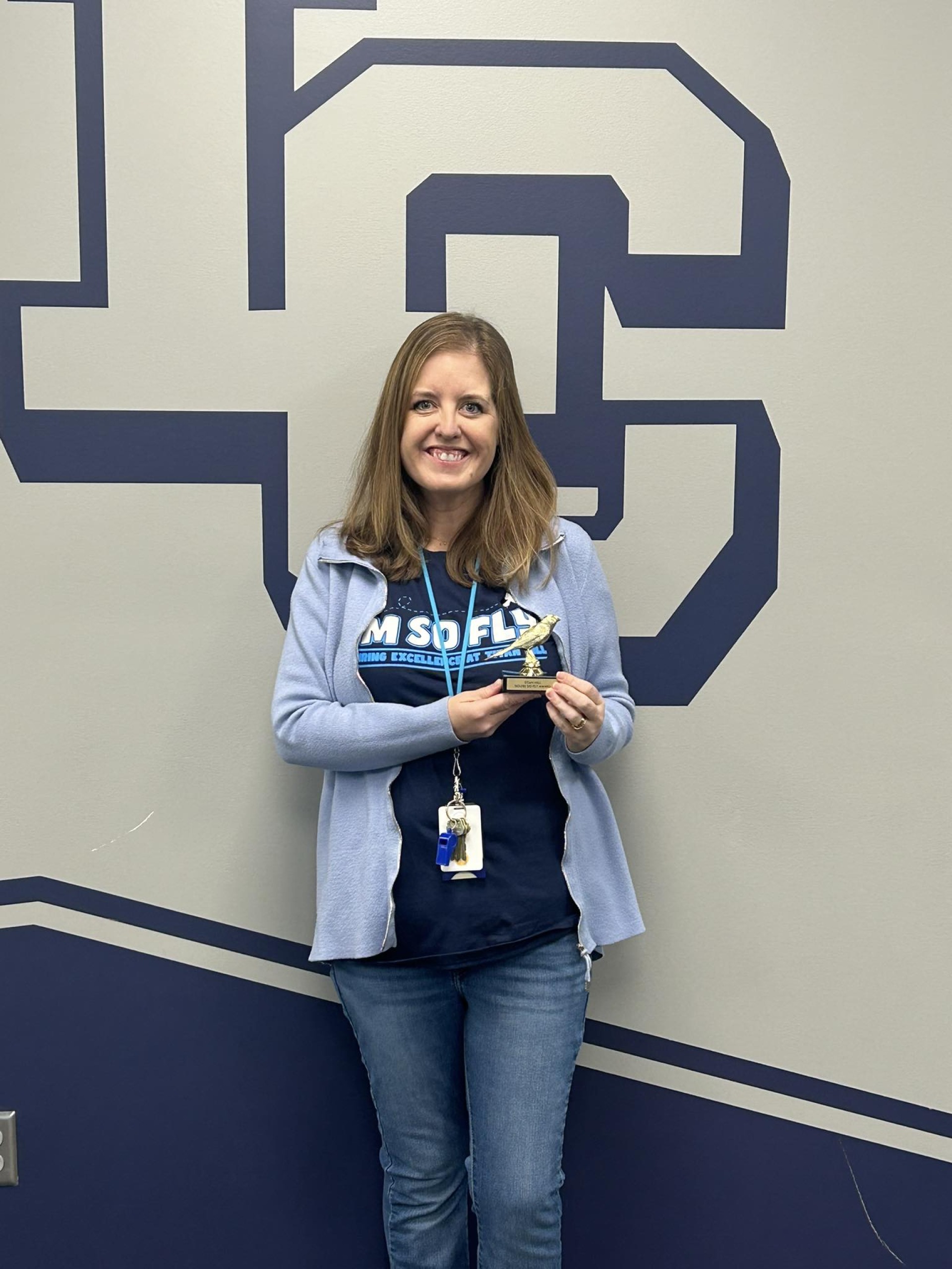Mrs. Nightser, librarian teacher, holding her "You\'re so Fly" award.