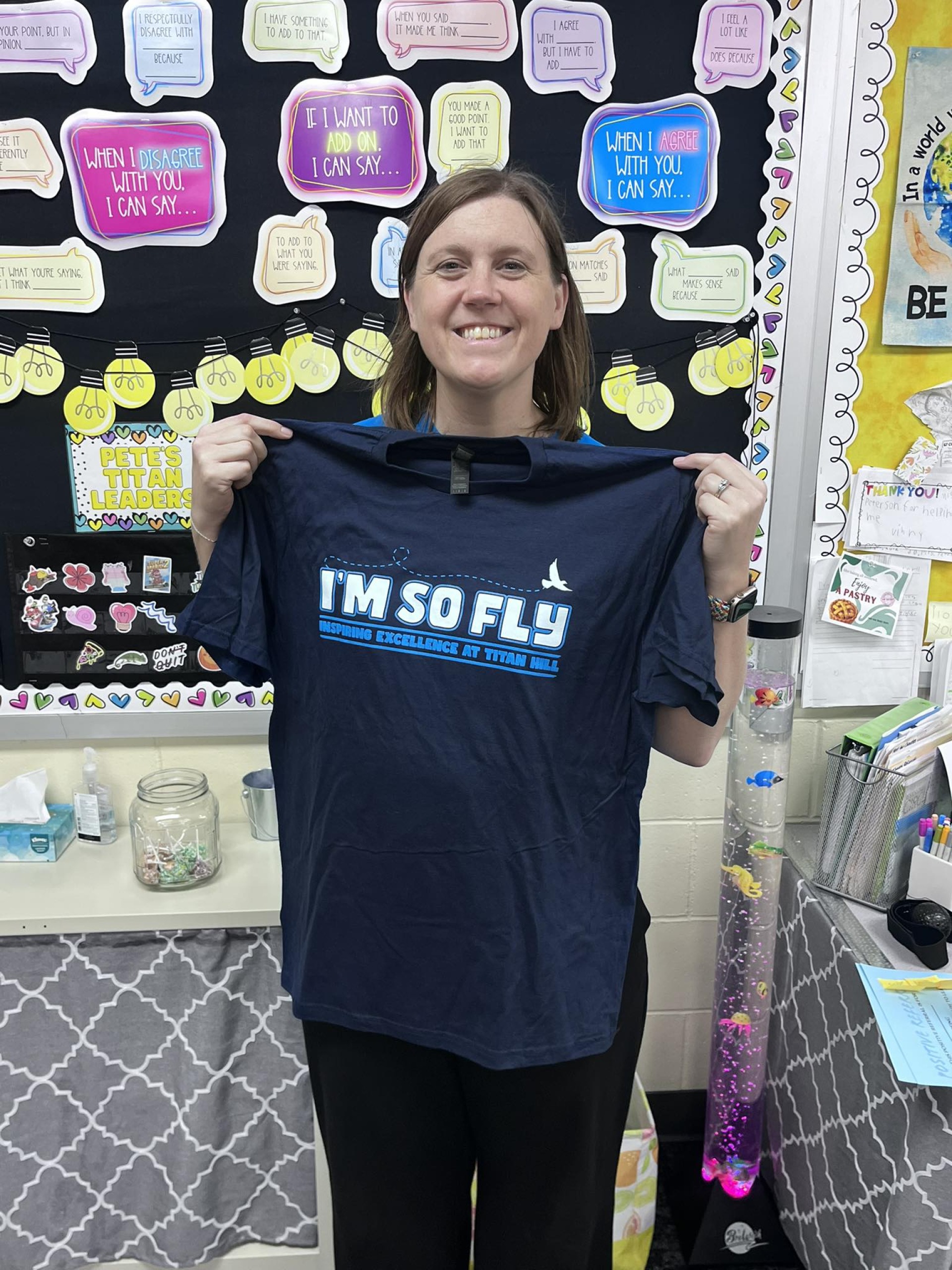 Ms. Petersen holding her "You\'re so Fly" staff award.